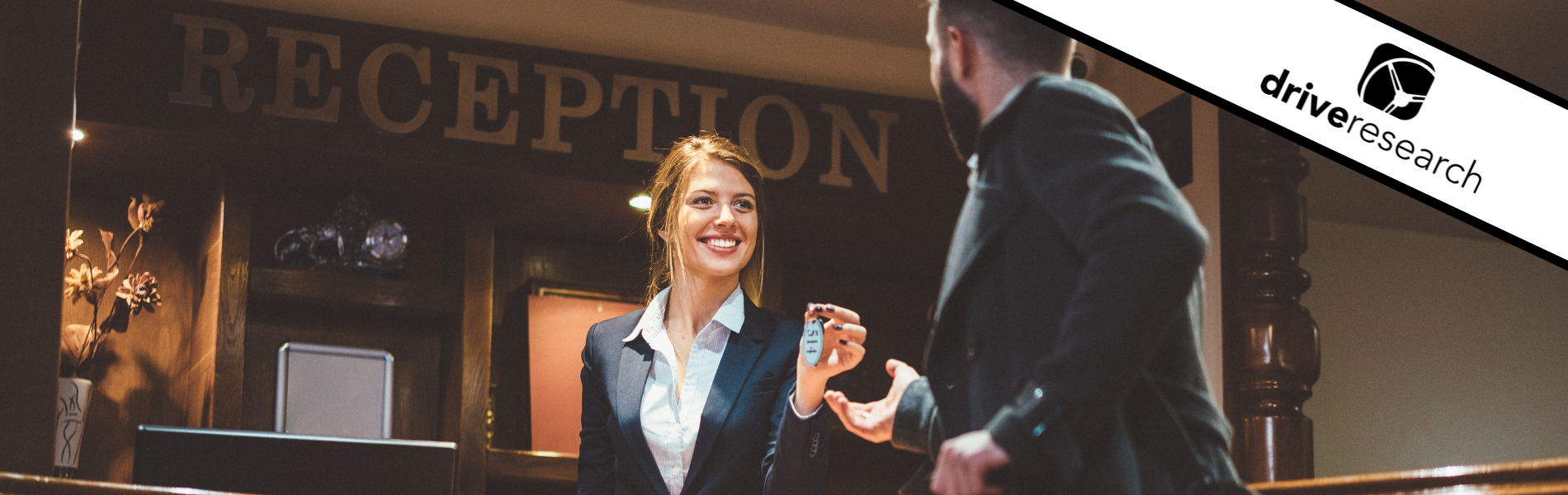 woman working at a hotel handing a guest his keys
