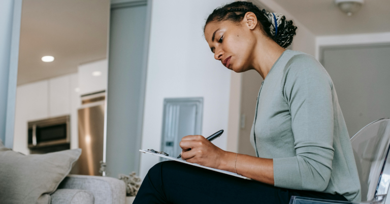 Concentrated female at home interviewer taking notes in clipboard
