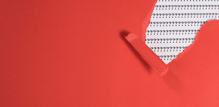 Red Paper Teared Revealing Question Mark On White Paper