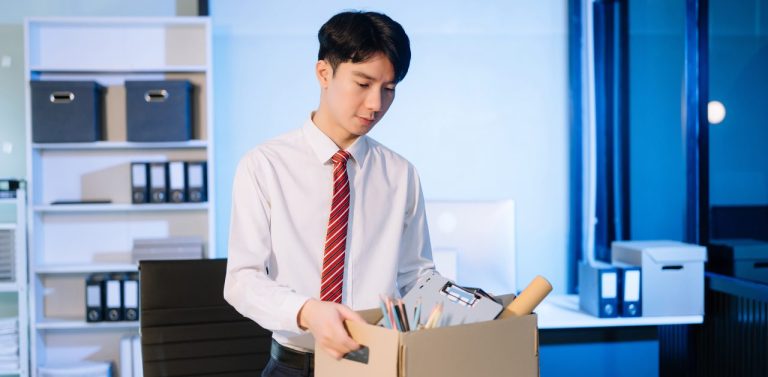 Young asian employee exiting his company with box of his things