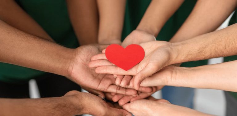close up of volunteers hands holding heart