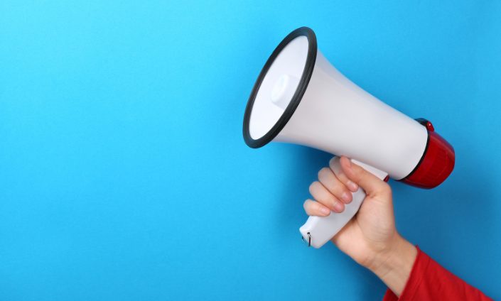 Hand Holding Megaphone Over Blue Background