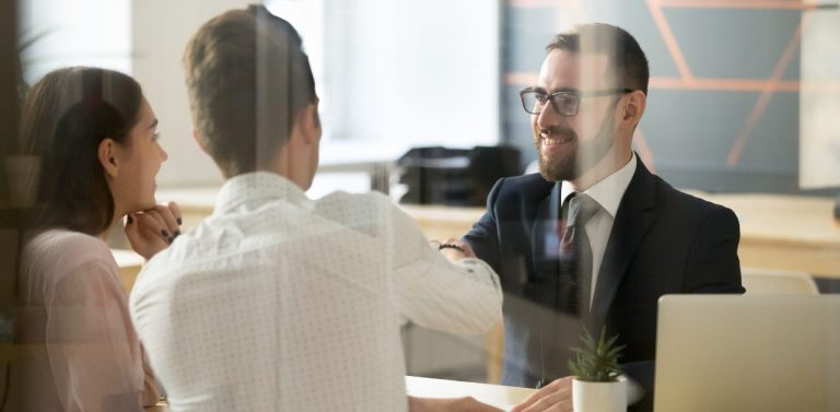 Bank teller shaking hands with clients in office