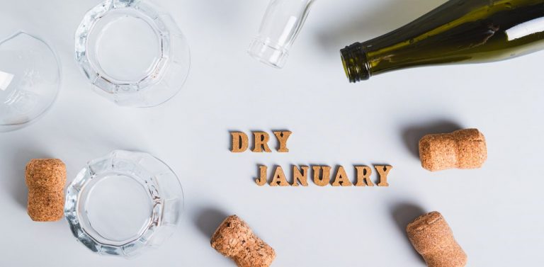 Dry January concept, empty glasses, bottles and corks on a gray background