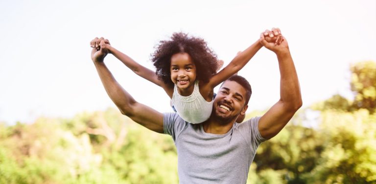 Child flying on father shoulders