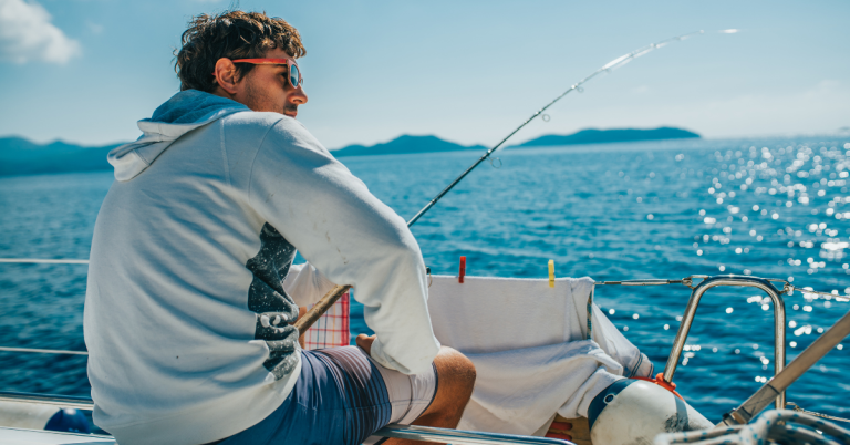 Man with sunglasses sitting and fishing on boat